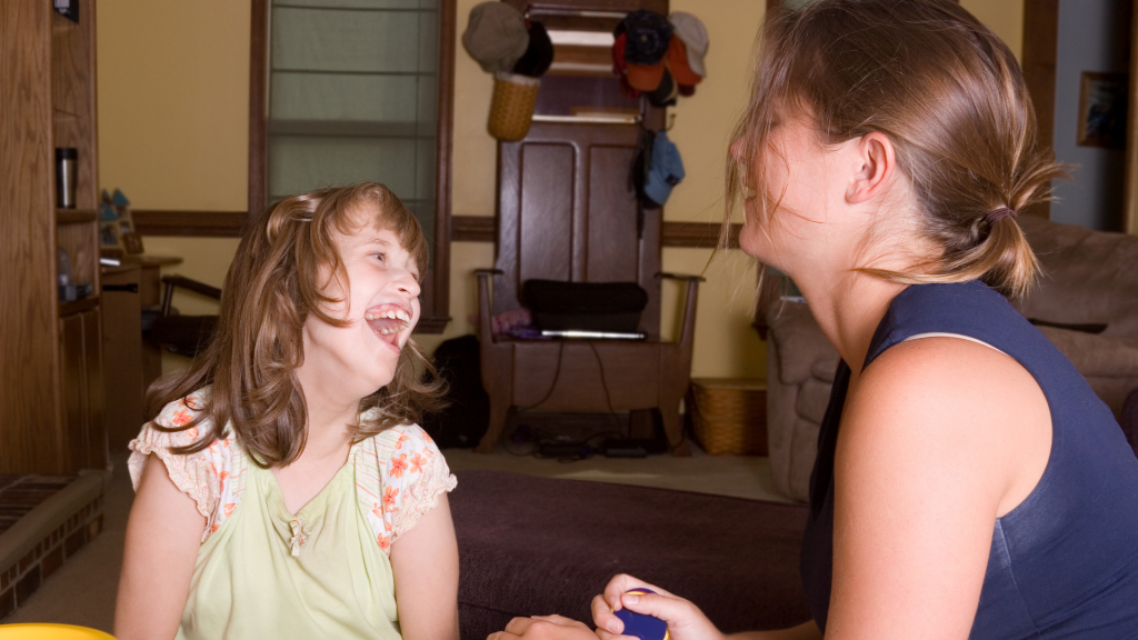 A woman and a girl sharing a joyful moment, laughing together with genuine happiness on their faces.